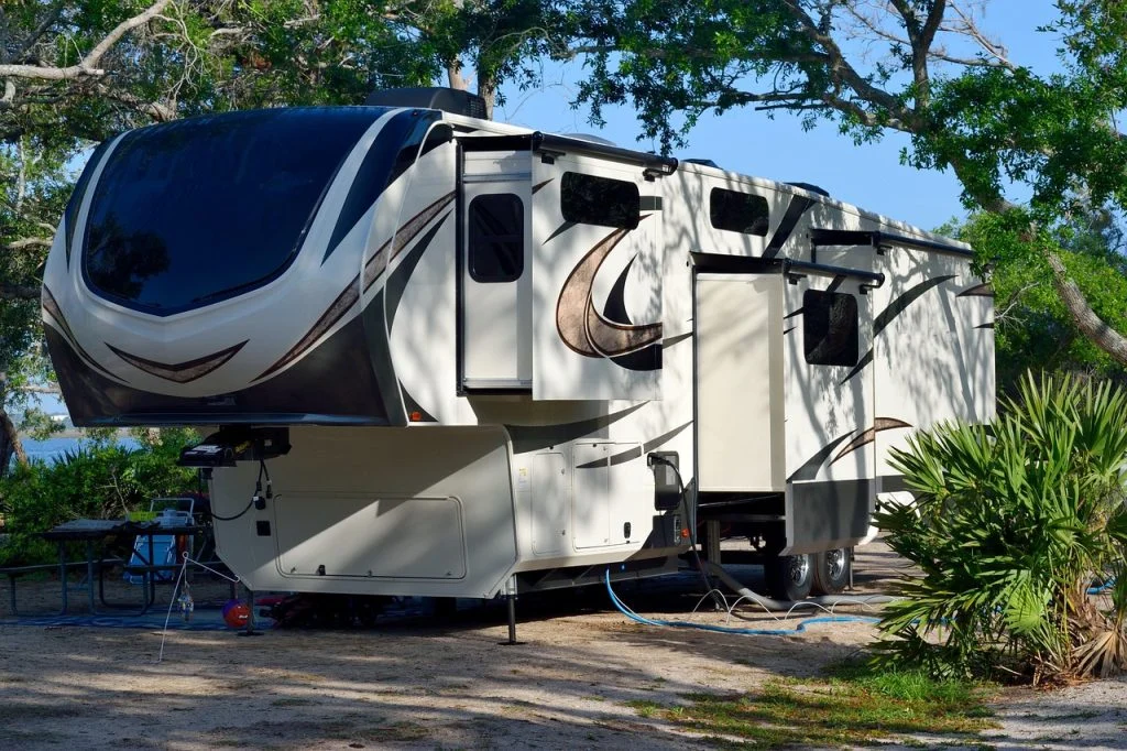 Toy hauler RV with fold-down side patio deck extending from the living area, creating an elevated outdoor seating space